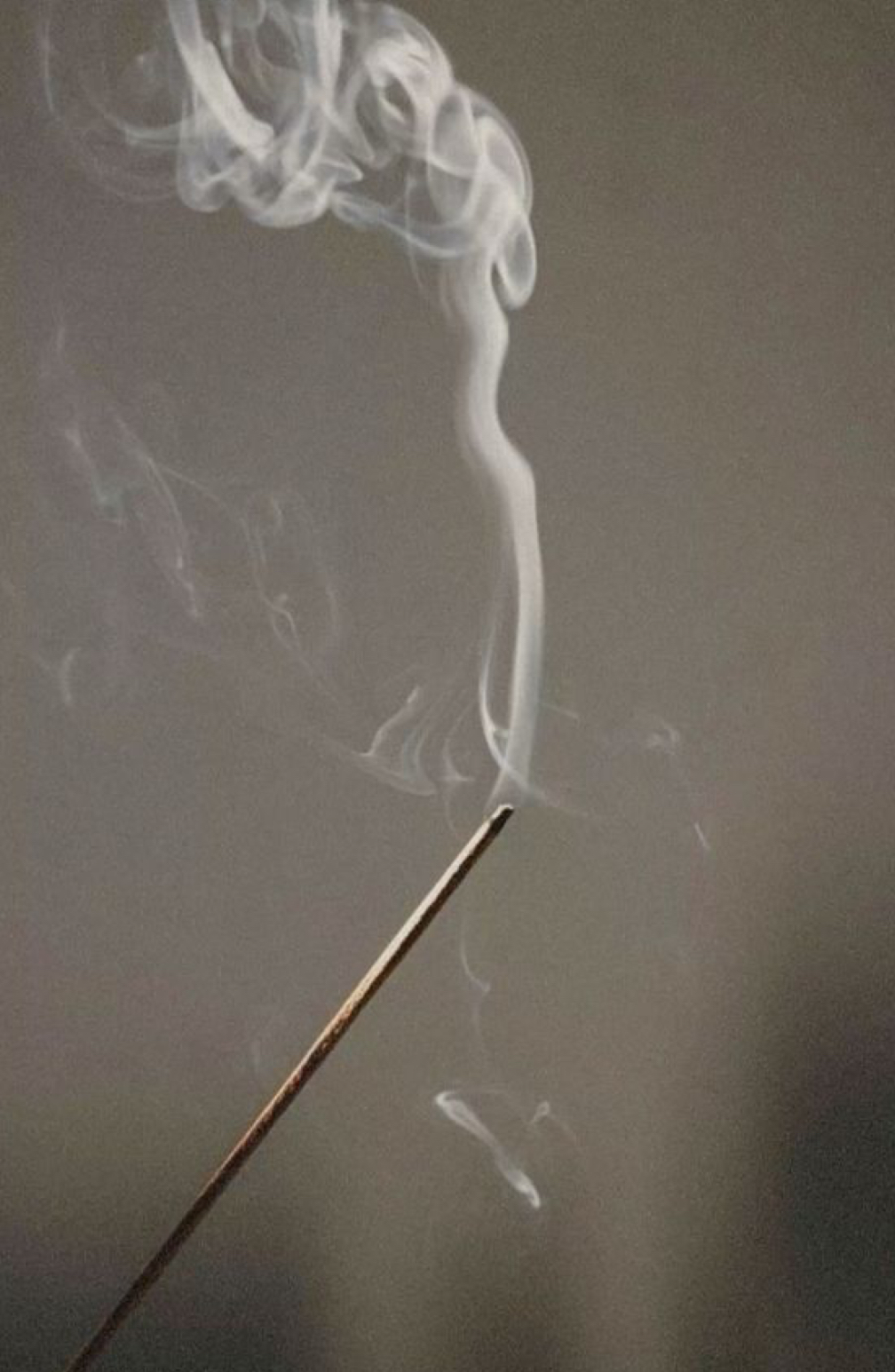 Incense smoke rising in contemplative space representing transformation